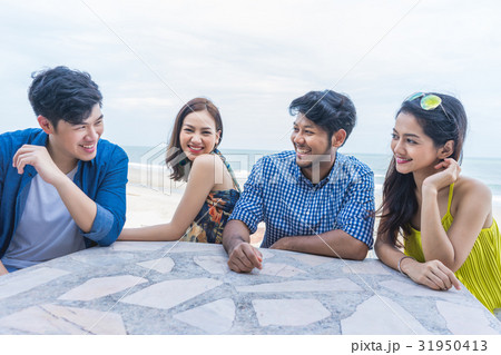 Four people are sitting, chatting and laughing together. 31950413