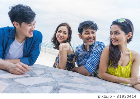 Four male and female friends are smiling, sitting and happily talking. Four male and female friends are smiling, sitting and happily talking. 31950414