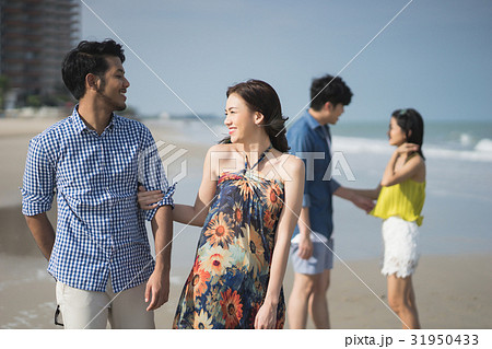 A photo of two couples arm in arm and being happy on the beach. A photo of two couples arm in arm and being happy on the beach. 31950433