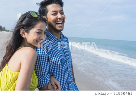 a couple is watching something and smiling happily on the beach. a couple is watching something and smiling happily on the beach. 31950463