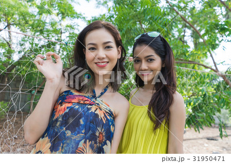 two beautiful women are standing near a net and smiling. two beautiful women are standing near a net and smiling. 31950471
