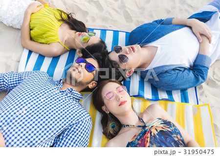 Four people with sunglasses are lying on the beach and sleeping Four people with sunglasses are lying on the beach and sleeping 31950475