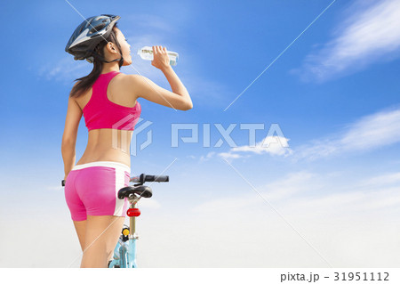 Young woman drinking water with folding bike Young woman drinking water with folding bike 31951112