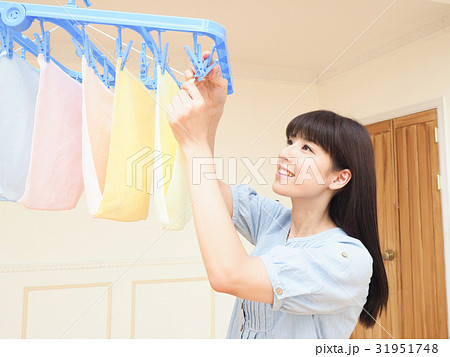室内干しした洗濯物を取り込む女性 室内干しした洗濯物を取り込む女性 31951748