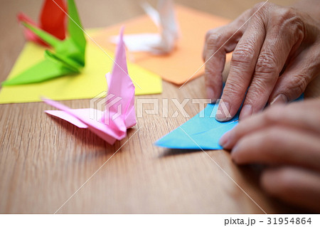 折り紙 鶴ツル つる カラフル テーブル 机 水色 ピンク オレンジ 黄色 白 黄緑色 赤 の写真素材