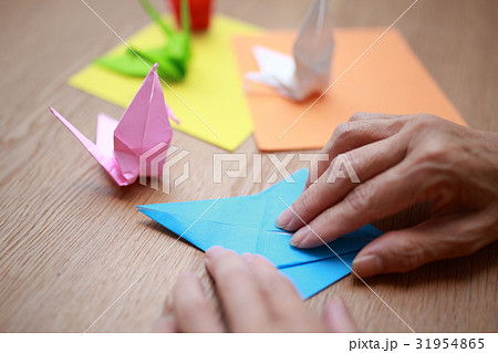 折り紙 鶴ツル つる カラフル テーブル 机 水色 ピンク オレンジ 黄色 白 黄緑色 赤 の写真素材