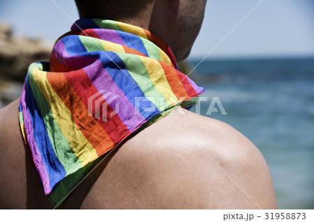 man with a rainbow flag in front of the ocean 31958873