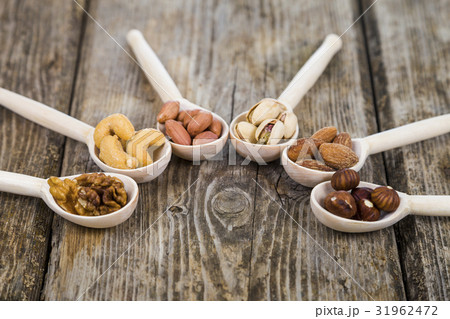 Nuts in a wooden spoons on a  wooden table. 31962472