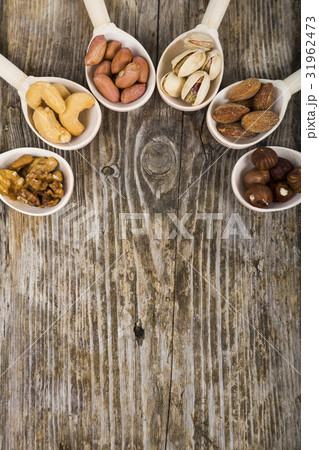 Nuts in a wooden spoons on a  wooden table. 31962473
