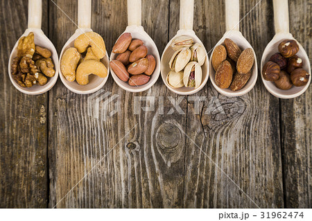Nuts in a wooden spoons on a  wooden table. 31962474