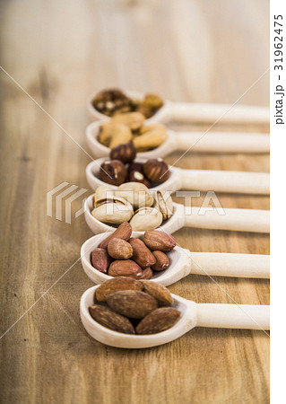 Nuts in a wooden spoons on a wooden table. Nuts in a wooden spoons on a wooden table. 31962475