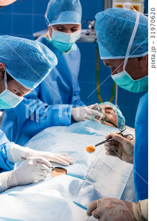 Surgeons performing operation in operation room Surgeons performing operation in operation room 31970620