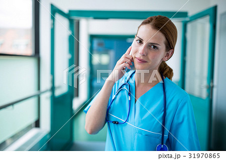 Portrait of surgeon talking on mobile phone in corridor Portrait of surgeon talking on mobile phone in corridor 31970865