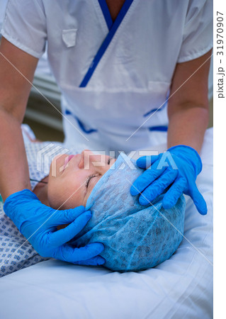 Nurse putting a surgical cap to patient 31970907