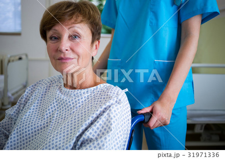 Portrait of patient sitting on wheel chair with nurse standing behind 31971336