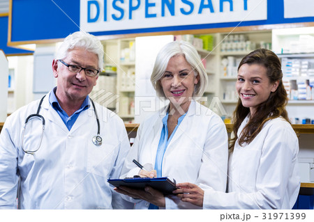 Pharmacists writing on clipboard in pharmacy Pharmacists writing on clipboard in pharmacy 31971399
