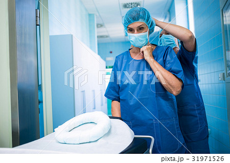 Nurse helping a surgeon in tying surgical mask Nurse helping a surgeon in tying surgical mask 31971526