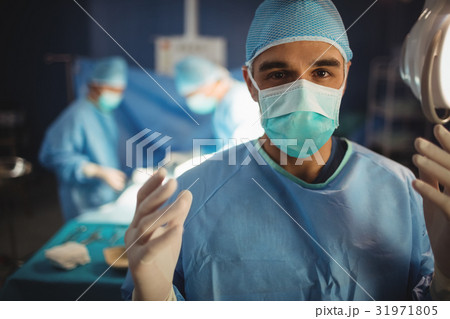 Portrait of male surgeon preparing for operation in operation room Portrait of male surgeon preparing for operation in operation room 31971805