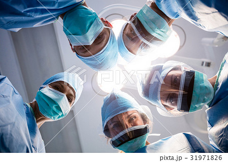 Group of surgeons looking at camera in operation room Group of surgeons looking at camera in operation room 31971826