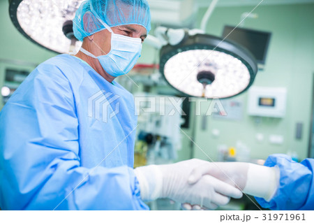 Surgeons shaking hands in operation room Surgeons shaking hands in operation room 31971961
