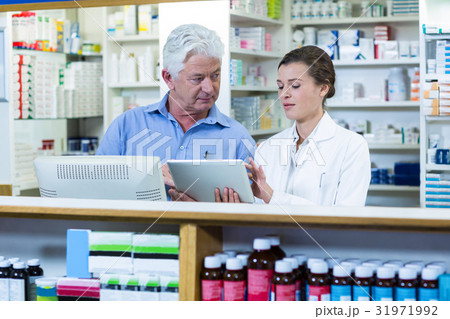 Pharmacists using digital tablet at counter 31971992