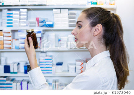Pharmacist checking a bottle of drug 31972040