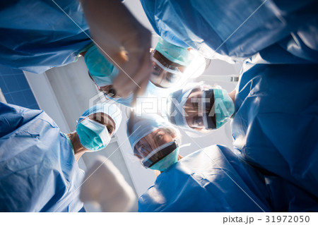 Group of surgeons looking at camera in operation room 31972050