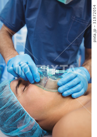 Male surgeon putting an oxygen mask on patient 31972054