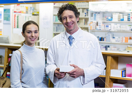Smiling customer and pharmacist holding drug box in pharmacy Smiling customer and pharmacist holding drug box in pharmacy 31972055