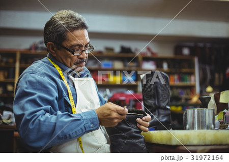 Shoemaker applying glue on shoe 31972164