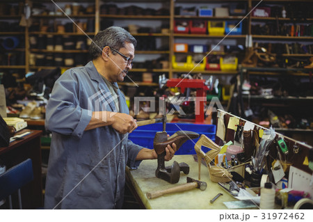 Shoemaker hammering on a shoe 31972462