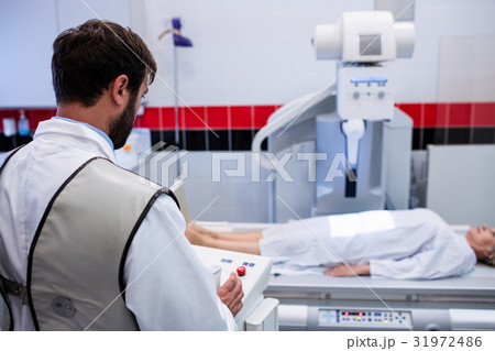 Doctor using x-ray machine to examine patient Doctor using x-ray machine to examine patient 31972486