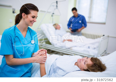Nurse consoling a patient in hospital ward 31972562