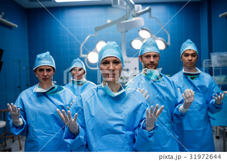 Portrait of surgeons standing with hands raised in operation room Portrait of surgeons standing with hands raised in operation room 31972644