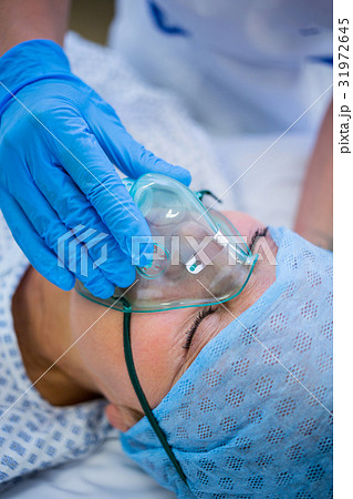 Nurse placing an oxygen mask on the face of a patient Nurse placing an oxygen mask on the face of a patient 31972645