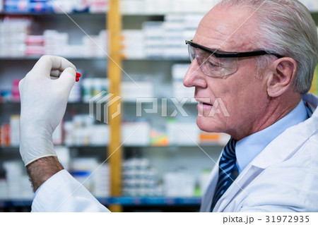 Pharmacist checking a capsule 31972935