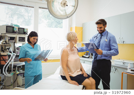 Male doctor interacting with a patient while nurse looking at x-ray Male doctor interacting with a patient while nurse looking at x-ray 31972960
