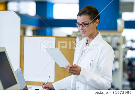 Pharmacist looking at prescription and writing on book Pharmacist looking at prescription and writing on book 31972999