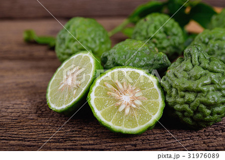 whole and half cut kaffir on wooden background whole and half cut kaffir on wooden background 31976089