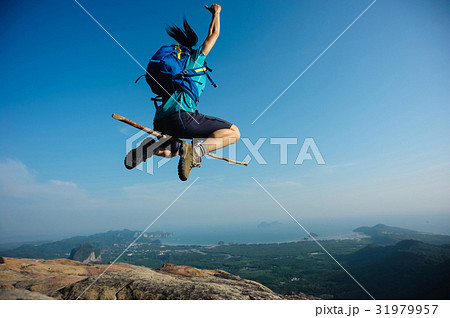 cheering woman jumping on rocky mountain top 31979957