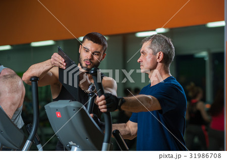 Senior man working with personal trainer in gym Senior man working with personal trainer in gym 31986708