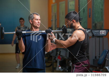 Personal trainer working with senior man in gym 31986709