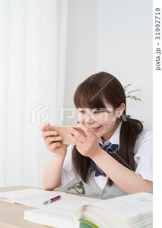 自宅学習しながらスマホを見る女子高生 自宅学習しながらスマホを見る女子高生 31992719