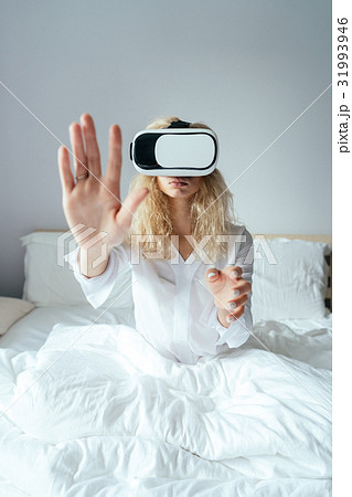 Girl sitting on a bed with VR headset Girl sitting on a bed with VR headset 31993946