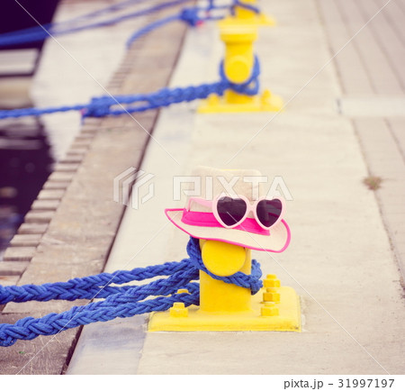 Straw hat and sunglasses in port with yacht 31997197
