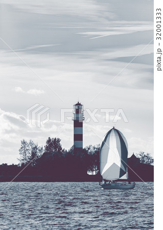 Sailboat sailing past lighthouse 32001333