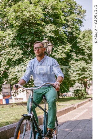 Businessman riding bicycle to work on urban street 32002151
