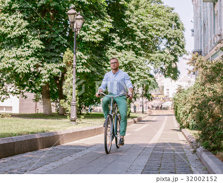 Businessman riding bicycle to work on urban street 32002152