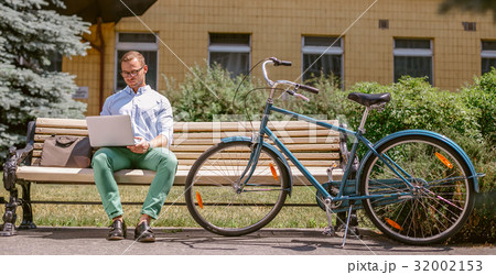 Businessman working on laptop sitting on a bench 32002153