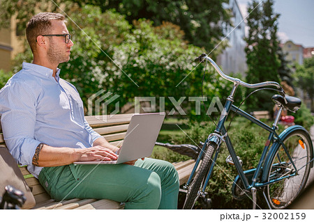 A young man is sitting on a bench and working on a 32002159